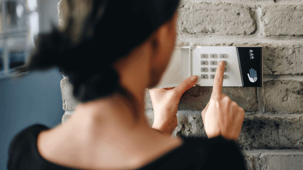 person entering a code at a wall-mounted alarm keypad