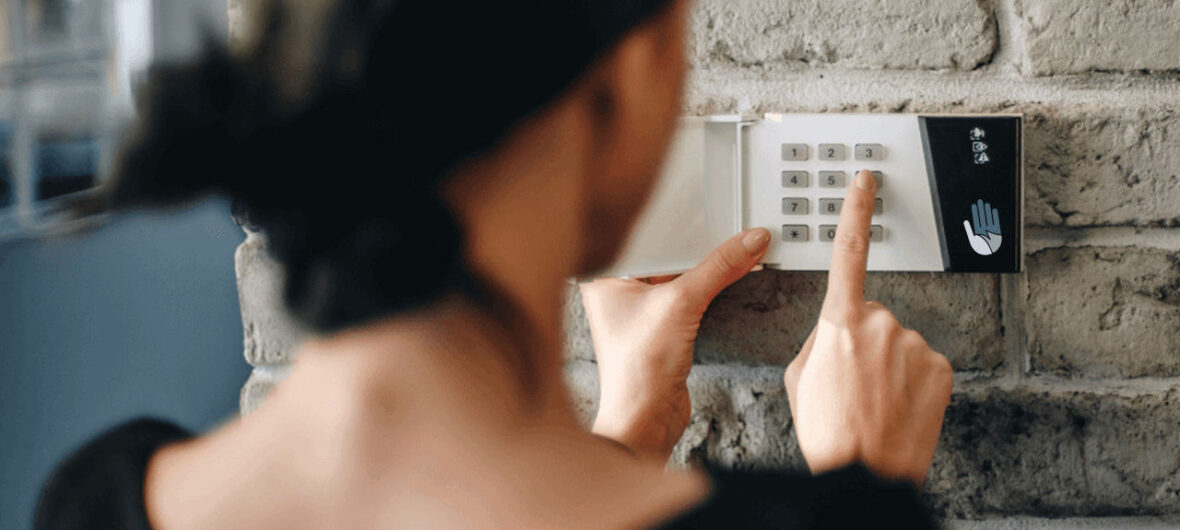 person entering a code at a wall-mounted alarm keypad